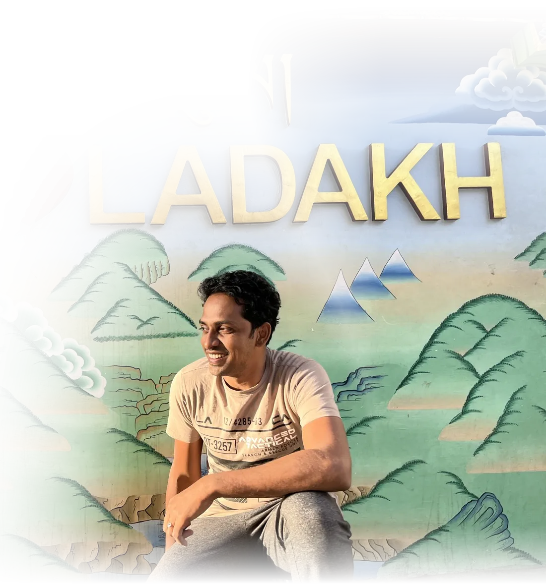 Navarasu laughing in front of a painted Ladakh mural